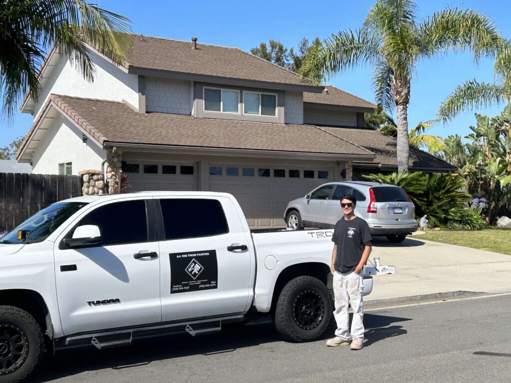 Man in front of work truck that is parked in front of a house